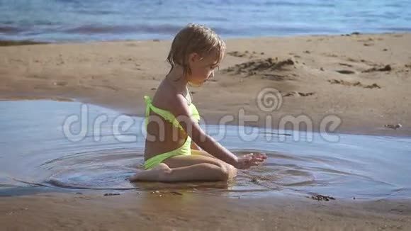 可爱的金发小女孩在湖边玩沙子视频的预览图