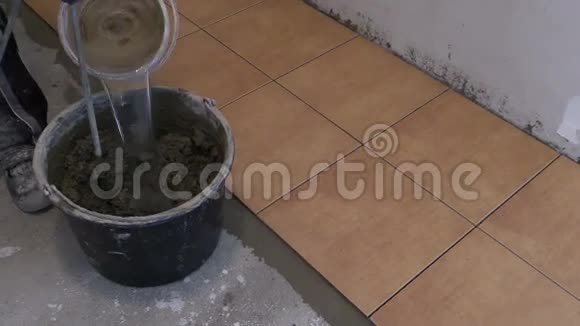 把水倒在桶里的混合物上混合瓷砖胶视频的预览图