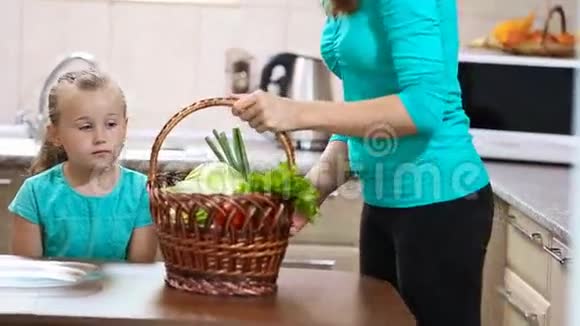 女孩帮妈妈从篮子里拉蔬菜视频的预览图