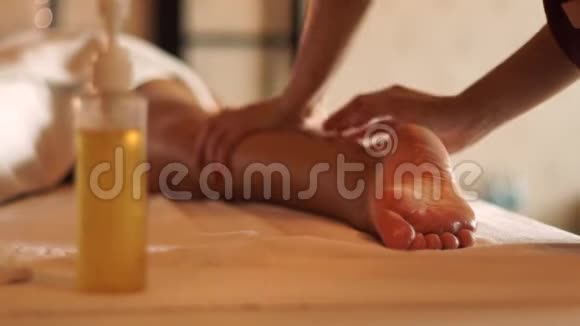 年轻女子在度假水疗沙龙里用油做腿部按摩在豪华水疗中心接受身体按摩的年轻女性视频的预览图