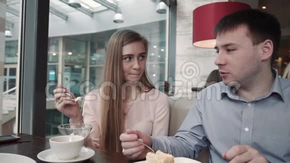 漂亮的年轻夫妇在咖啡馆里使用智能手机看着展示微笑视频的预览图