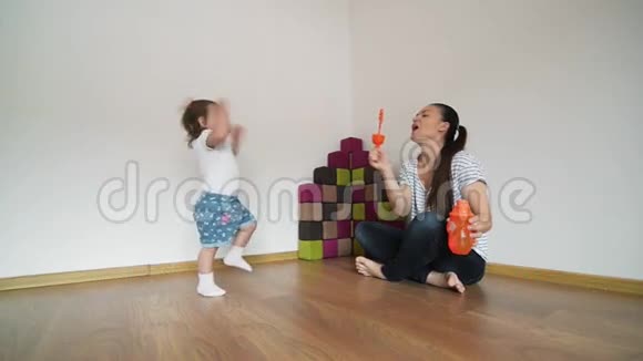年轻的母亲给女儿吹泡泡女孩笑着玩视频的预览图