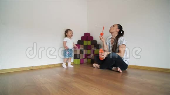 年轻的母亲给女儿吹泡泡女孩笑着玩视频的预览图