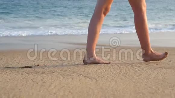 雌性的脚在沙滩上行走背景是海浪年轻女子踩沙的腿视频的预览图