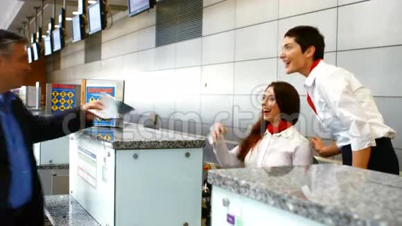 两名女机场工作人员在登记台检查护照并与男子互动视频的预览图