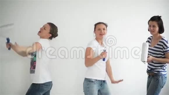 朋友在家修理有趣的女孩跳舞在公寓里粉刷墙壁视频的预览图