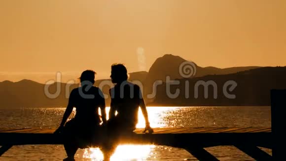 日落时分坐在桥上的年轻夫妇视频的预览图