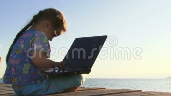 小女孩在海边玩电脑视频的预览图