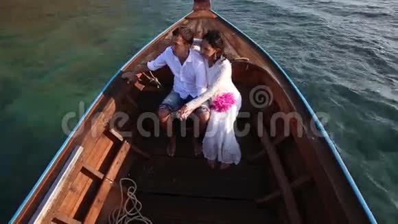 日出时漂在船上的新娘和新郎视频的预览图