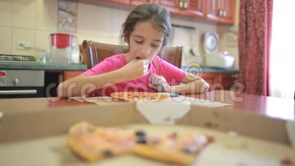 吃披萨和水果的女孩在餐桌旁的厨房里玩电话视频的预览图