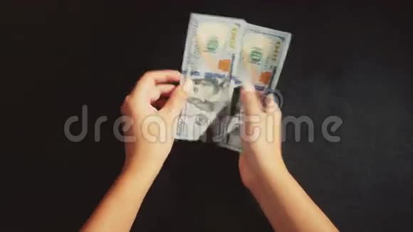 女人的手数着黑色背景上的一包钱视频的预览图