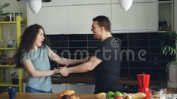 快乐又迷人的年轻一对恋爱中的情侣在假日的厨房里一起跳摇滚舞视频的预览图