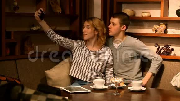 年轻女子在咖啡馆里用手机拍照视频的预览图