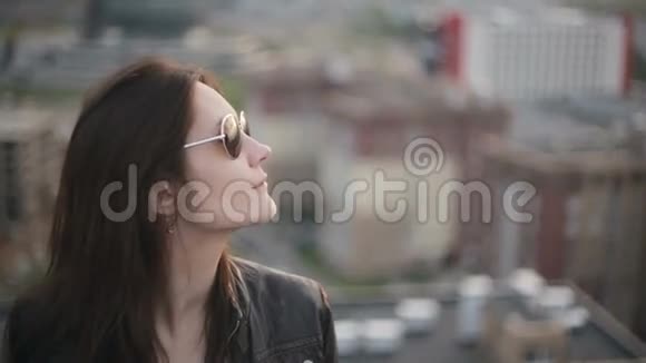 日落时分戴太阳镜的女孩站在屋顶上视频的预览图