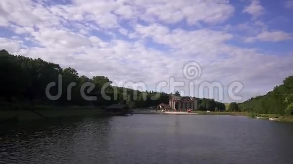绿林环绕的美丽湖泊湖滩上的豪华度假村蓝天背景视频的预览图