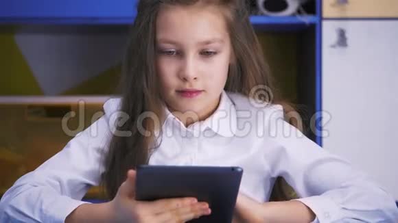 在图书馆学习的女孩用平板电脑做课后作业小学儿童读物视频的预览图
