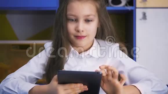 在图书馆学习的女孩用平板电脑做课后作业小学儿童读物视频的预览图