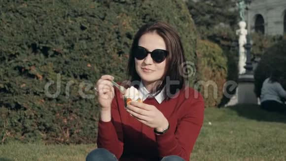 快乐的年轻女子在阳光明媚的一天在公园草地上享受冰淇淋视频的预览图