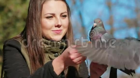 快乐的女孩用手喂养鸽子视频的预览图