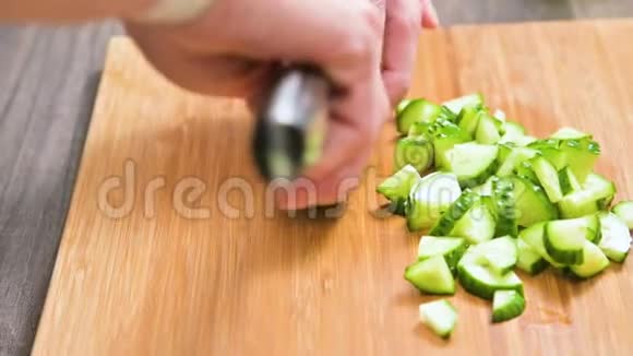 一只雌性的手在木切割板上切一刀黄瓜做沙拉家庭厨房健康视频的预览图