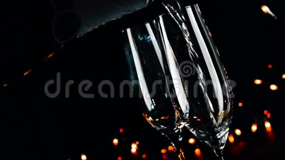 在黑色暗光背景下两瓶带有金色气泡的香槟酒杯新年气氛视频的预览图