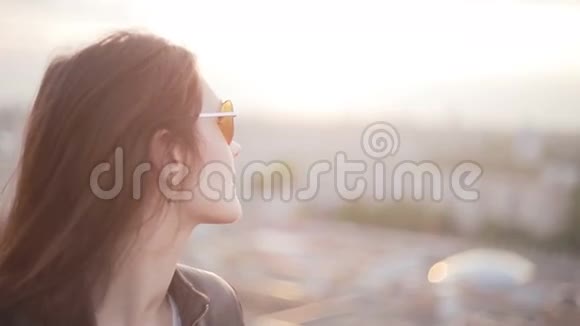 日落时分戴太阳镜的女孩站在屋顶上视频的预览图