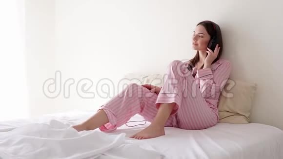 在床上戴着大耳机听音乐的女人视频的预览图
