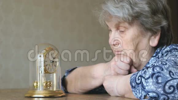 老妇人用钟摆看桌钟视频的预览图