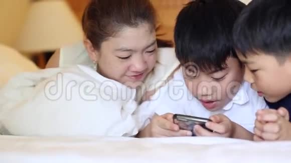 快乐的亚洲家庭正在玩平板电脑微笑着躺在床上视频的预览图