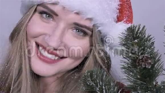靠近圣诞老人帽子上的可爱女孩树枝享受降雪视频的预览图