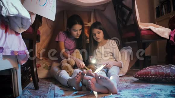 两个穿睡衣的女孩晚上在地板上读故事视频的预览图