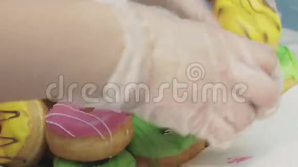 戴手套的女孩数着盒子里被釉覆盖的五颜六色的甜甜圈面包店糖果视频的预览图