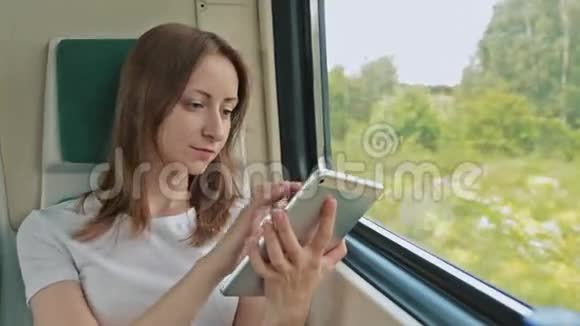 坐在火车上拿着平板电脑的年轻女子视频的预览图