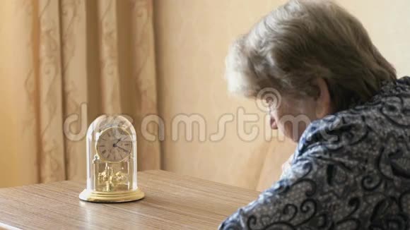 老妇人用钟摆看桌钟视频的预览图