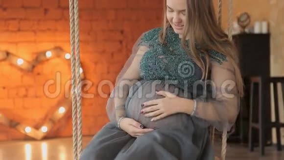 孕妇坐在装饰的秋千上家庭观念生育观念视频的预览图