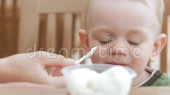 妈妈用勺子喂小儿子吃冰淇淋他们坐在一家街头咖啡馆里这个男孩真的很喜欢视频的预览图