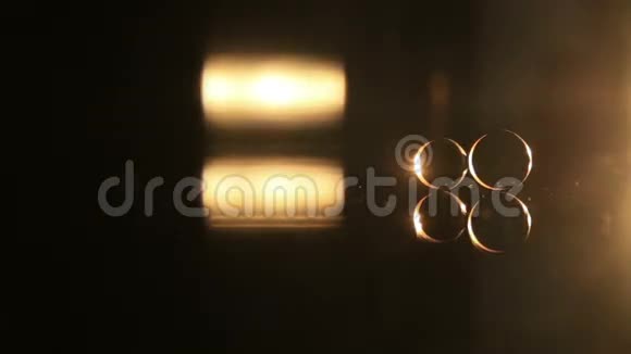 两个金色结婚戒指在镜面上黑暗的背景照明打开和关闭灯与温暖视频的预览图
