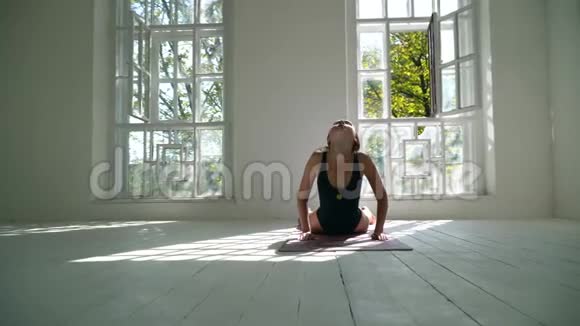 红发年轻健康的白种人女人在白色的大房间里的垫子上练习瑜伽年轻女子运动视频的预览图