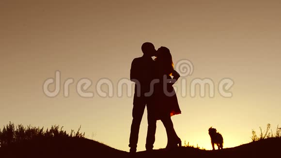情侣在爱情里亲吻走日落的剪影自然慢动作视频男人和女人的爱情轮廓与一个视频的预览图