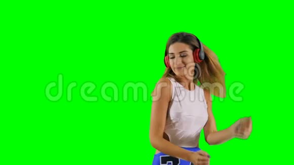 戴耳机的时髦女孩在绿色背景下听音乐和跳舞视频的预览图