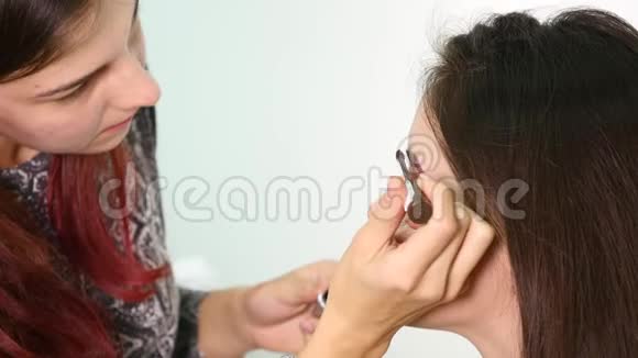 化妆师画一个年轻女孩的眉毛深色专业油漆视频的预览图