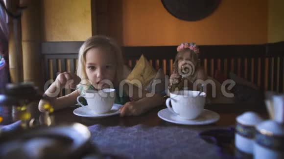 两个可爱的金发小女孩在咖啡馆里喝茶视频的预览图