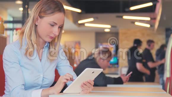 漂亮的年轻女子在咖啡馆里使用ipad平板触摸屏视频的预览图