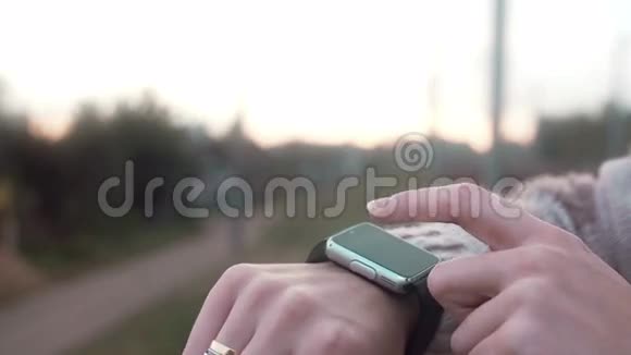 一位女士在农村背景下使用她的智能手表触摸屏设备视频的预览图