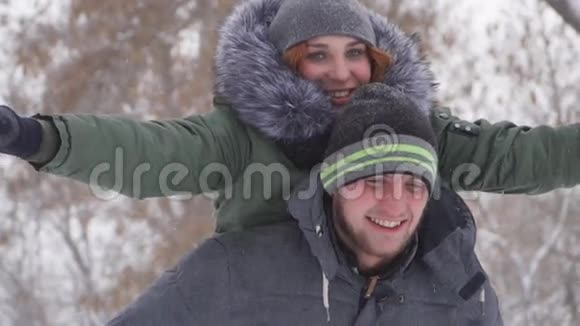 可爱的年轻人在雪地里的树林里快乐地背着女友视频的预览图