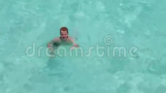 男孩少年在蓝色透明的海水中游泳挥动一只手马尔代夫视频的预览图