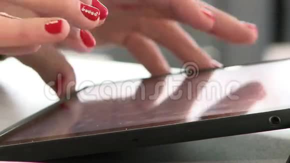 女人的双手用鲜红的指甲在平板上工作视频的预览图