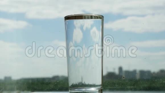 玻璃与水在模糊的蓝天和城市背景变化的焦点1920x1080视频的预览图