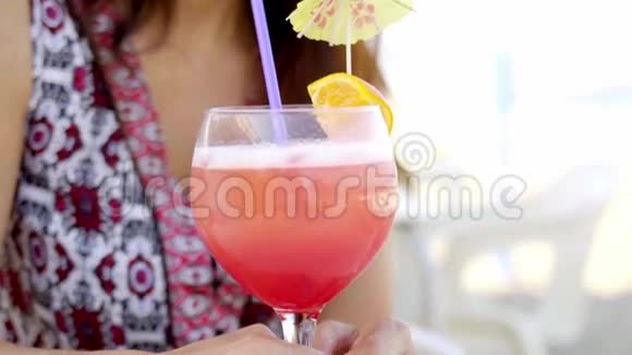 在海滩上喝鸡尾酒的漂亮女人视频的预览图