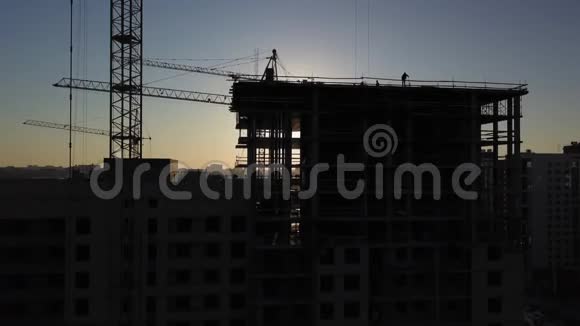 日落时施工现场建筑物附近建筑起重机的剪影视频的预览图